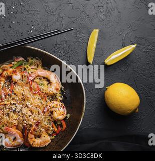 Cibo, mescolare gli spaghetti con verdure e gamberetti nel recipiente nero Foto Stock