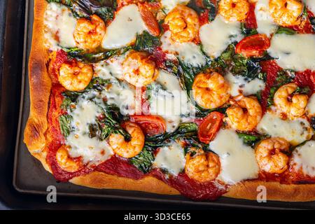 Pizza con gamberi, pomodori e spinaci, primo piano. Sfondo pizza mediterranea. Foto di alta qualità Foto Stock