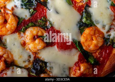 Pizza con gamberi, pomodori e spinaci, primo piano. Sfondo pizza mediterranea. Foto di alta qualità Foto Stock