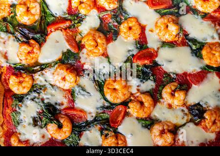Pizza con gamberi, pomodori e spinaci, primo piano. Sfondo pizza mediterranea. Foto di alta qualità Foto Stock