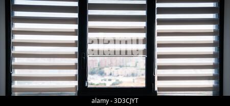 Tre finestre moderne con tende a rullo zebra che filtrano la luce del giorno in un appartamento minimalista Foto Stock