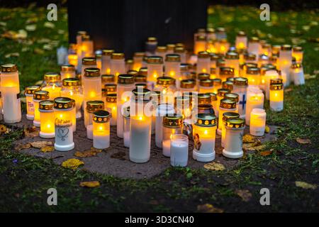 Candele accese su un cimitero di notte, calde fiamme che creano un'atmosfera commemorativa calma ed emotiva tra le tombe. Foto Stock