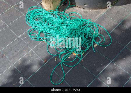 Tubo flessibile per legare il giardino visualizzato sulla membrana per erbacce. Concetto di fornitura di giardinaggio Foto Stock