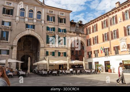 Italia, Verona - 1 ottobre 2025: Vivace Piazza dei signori a Verona piena di turisti in una soleggiata giornata autunnale, circondata da colorati bui storici Foto Stock