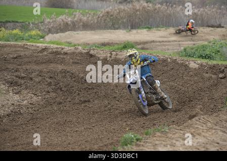 Il pilota di motocross sta guidando la sua moto in una curva su una pista sterrata Foto Stock