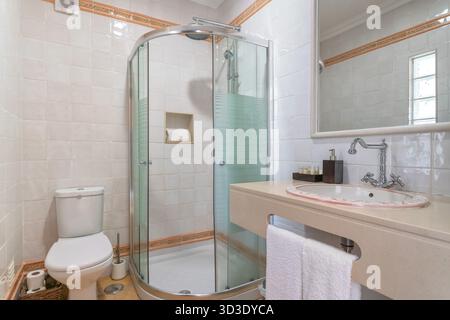 Bagno pronto per la clientela con arredi eleganti, bagno luminoso con finiture moderne e presentazione ordinata, bagno ben organizzato con box in vetro Foto Stock