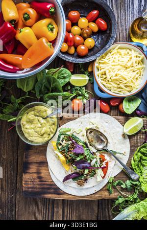 Preparare fajitas o tortillas messicane tradizionali su un tavolo di legno, cibo semplice da strada. Vista dall'alto Foto Stock