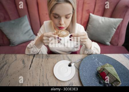 Ritratto di giovane bellissima femmina bere il tè e minuziosamente guardando fuori del coffee shop finestra mentre godendo il suo tempo libero da soli, nice busi Foto Stock
