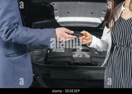 Meccanico che consegna le chiavi della sua auto riparata nel servizio di riparazione auto Foto Stock