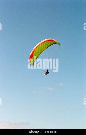 Parasailing persona in alto sopra l'oceano a Tenerife, Isole Canarie, con cieli blu e viste costiere, avventura e concetto di viaggio. Foto Stock
