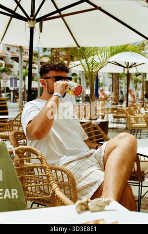 Uomo con occhiali da sole che si gode una pinta fredda di birra all'aperto durante una vacanza al sole a Tenerife, atmosfera rilassata con cieli azzurri Foto Stock