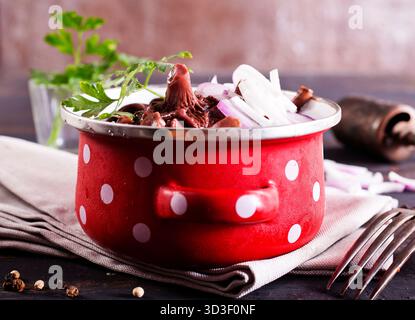 funghi commestibili con cipolla in un recipiente di metallo Foto Stock
