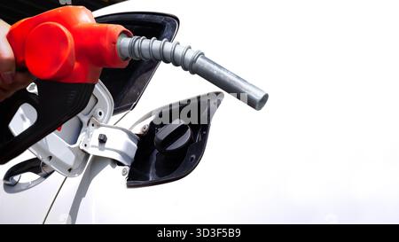 Primo piano di un ugello rosso della pompa del carburante inserito nel serbatoio del gas di una vettura, concetto di rifornimento, manutenzione del veicolo, energia di trasporto, benzina, e fue Foto Stock