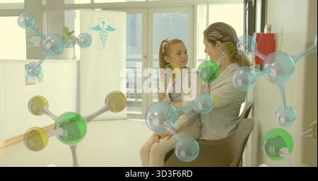 Madre e figlia sedute che abbracciano le sedie in clinica, con striscione caduceo e modello molecolare Foto Stock