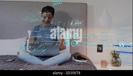 Uomo che analizza i dati finanziari sul laptop in camera da letto, con cuffie e tazza per smartphone Foto Stock