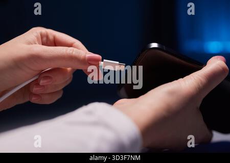 Le ricariche per le mani femminili caricano il telefono. Primo piano USB Type-C. Foto Stock