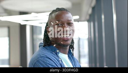 Uomo in piedi che indossa camicia in denim e T-shirt in un moderno corridoio d'ufficio con luci circolari Foto Stock