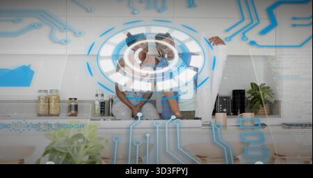 Coppia che indossa occhiali VR con interfaccia olografica nella cucina di casa, con progetti Foto Stock