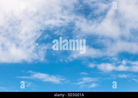 Una vista serena di un cielo blu adornato da nuvole bianche sparse, creando un motivo rilassante. L'immagine cattura la bellezza del tessuto naturale delle nuvole Foto Stock