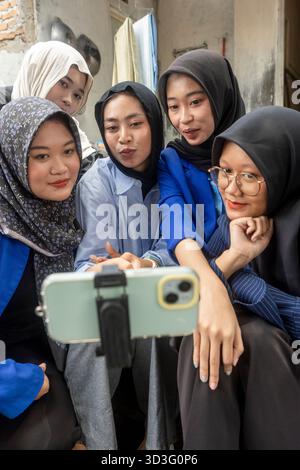 Un gruppo di donne scatta un allegro selfie mentre si gode una pausa dalla creazione di progetti Batik utilizzando tecniche tradizionali. Sono riuniti insieme, Foto Stock