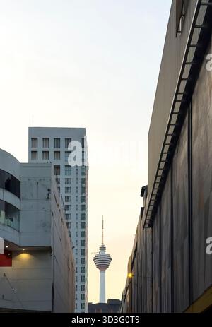 La Kuala Lumpur Tower sorge maestosamente nel paesaggio cittadino, incorniciata tra due alti edifici in una strada del centro cittadino, catturando il vibrante essenc urbano Foto Stock