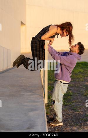Una coppia LGBT condivide un momento divertente all'aperto, mostrando connessione e gioia. Lo sfondo illuminato dal sole mette in risalto la loro felicità e il calore della loro Foto Stock