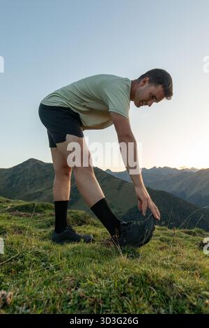Un uomo intraprende un'esilarante corsa sulle montagne mozzafiato dei Pirenei. Viene catturato estendendosi, circondato da una vegetazione lussureggiante e maestoso Foto Stock