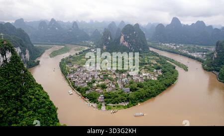 Vista aerea della città vecchia di Xingping circondata dal fiume li, con lussureggianti montagne carsiche verdi che formano uno sfondo mozzafiato, catturato da Laozhai Hil Foto Stock