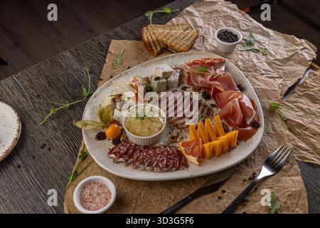 Tagliere di salumi con formaggi assortiti, affettati e antipasti su un tavolo rustico Foto Stock
