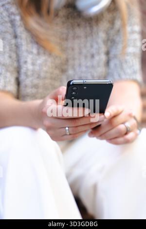 Primo piano di una donna che tiene lo smartphone all'aperto in ambienti urbani. Foto Stock