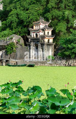 L'antica porta di pietra della Pagoda di Bich Dong, annidata tra montagne calcaree e lussureggiante vegetazione a Ninh Binh, Vietnam Foto Stock