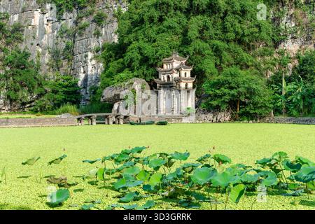 L'antica porta di pietra della Pagoda di Bich Dong, annidata tra montagne calcaree e lussureggiante vegetazione a Ninh Binh, Vietnam Foto Stock