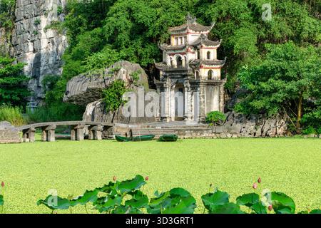 L'antica porta di pietra della Pagoda di Bich Dong, annidata tra montagne calcaree e lussureggiante vegetazione a Ninh Binh, Vietnam Foto Stock