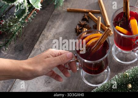 VIN brulé con bastoncini di arancia e cannella e decorazioni natalizie su un tavolo in legno Foto Stock