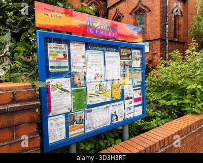 Manchester, Regno Unito - 30 settembre 2025: Bacheca blu della comunità St John's Centre a Manchester piena di volantini e poster pubblicitari Foto Stock