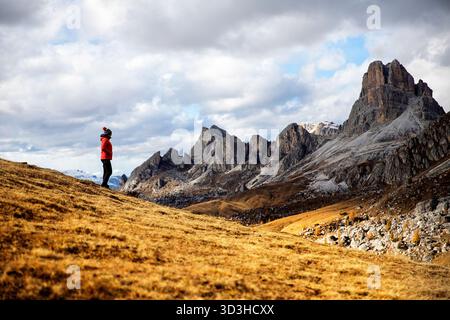 Un'escursionista turista donna in piedi che si gode la spettacolare vista panoramica autunnale dell'iconico Passo Giau nelle bellissime Dolomiti, Italia. Foto Stock