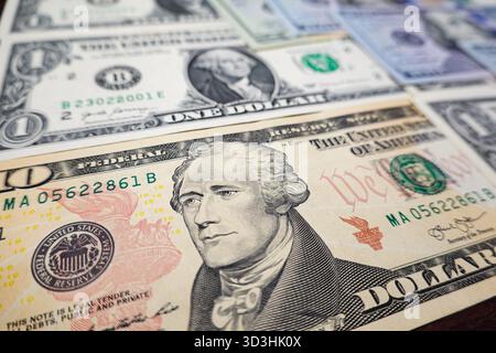 In questa illustrazione fotografica, una banconota da 10 dollari con Alexander Hamilton, con altre banconote statunitensi sullo sfondo. Foto Stock