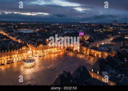 Vista serale di Place Ducale a Charleville-Mézières, Francia, storica piazza della città con edifici con portici illuminati, torre dell'orologio magenta e chiesa Foto Stock