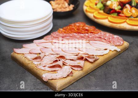 Cibo, tavola di legno con un assortimento di affettati, tra cui salame, prosciutto e mortadella, ideale per antipasti o buffet Foto Stock
