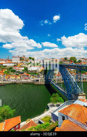 Vista panoramica del Ponte Dom Luis i che attraversa il fiume Douro con il colorato lungomare del quartiere di Ribeira e gli storici edifici sulle colline di Porto, Portogallo Foto Stock