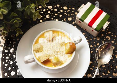 Cibo, ciotola calda di zuppa cremosa di zucca con parmigiano grattugiato e crostini dorati, serviti in un ambiente accogliente Foto Stock