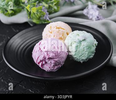 Cibo, tre cucchiai di gelato su un piatto scuro Foto Stock