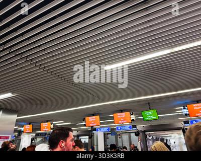 Balice, Polonia - 4 ottobre 2025: Una folla di viaggiatori si fila in una trafficata area di sicurezza dell'aeroporto di Cracovia con cartelli colorati. Foto Stock