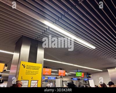 Balice, Polonia - 4 ottobre 2025: Vivace aeroporto di Cracovia con i viaggiatori a controllo passaporti sotto le luminose luci a soffitto e la segnaletica. Foto Stock