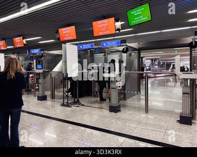 Balice, Polonia - 4 ottobre 2025: I passeggeri fanno la fila ai banchi di controllo passaporti sotto i cartelli luminosi dell'aeroporto di Cracovia Polonia. Foto Stock