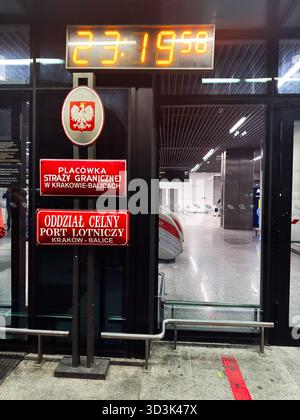 Balice, Polonia - 4 ottobre 2025: Aeroporto di Cracovia con cartelli rossi al confine, emblema dell'aquila polacca e porte in vetro. Foto Stock