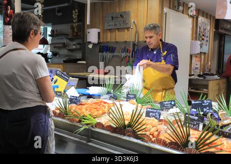 Pescivendolo e cliente a Les Halles de Pau, Nouvelle Aquitaine, Francia Foto Stock