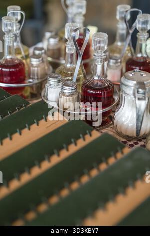 Vintage vecchie bottiglie di vetro contenenti olio, aceto, sale e pepe su un tavolo in un ristorante Foto Stock