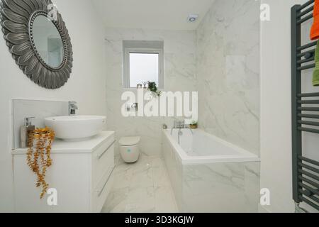 Bagno dal design moderno con pareti in marmo, vasca elegante e finiture eleganti in stile minimalista Foto Stock