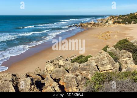 Vista diurna di Roche Beach (Roche Cove), con sabbia dorata, il movimento del mare Atlantico e formazioni rocciose di arenaria in primo piano. La scena captur Foto Stock